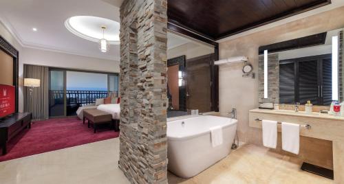 吉赞Grand Millennium Gizan的带浴缸的浴室和卧室
