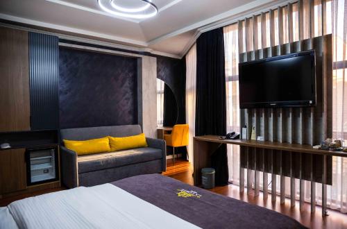 普里什蒂纳Hotel LaCorte Prishtina的酒店客房配有床、沙发和电视。