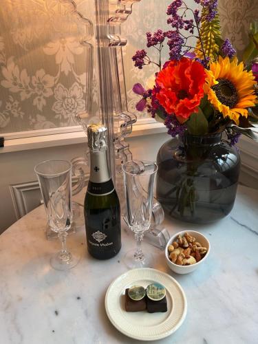 哈莱姆GuesthouseOne的一张桌子,上面放着一瓶葡萄酒、眼镜和鲜花