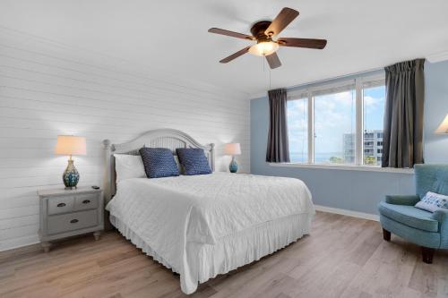 沃尔顿堡滩Heron 507- A Wave From It All的一间卧室配有一张带吊扇和蓝椅的床。