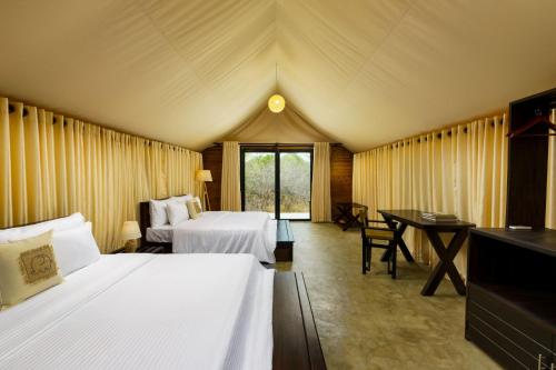 雅拉Makini Bush Camp, Yala的一间设有两张床的卧室和一张位于帐篷内的桌子