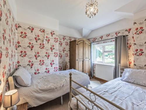西蒙兹亚特Flyby Cottage的一间卧室设有两张床和花卉壁纸