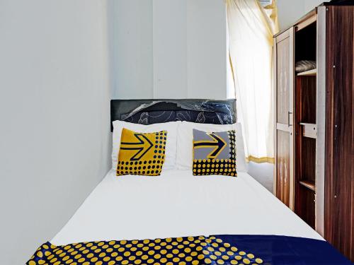 玛琅SPOT ON 1711 Serayu Sumbersari Residence的一间卧室配有黄色和蓝色枕头的床