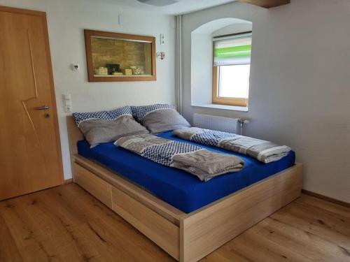 Schöne Wohnung am Bauernhof的一间卧室配有一张带蓝色床单的床和一扇窗户。