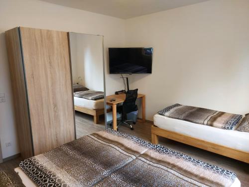 厄扎森Ferienwohnung Popp的一间卧室配有两张床和一张书桌及电视