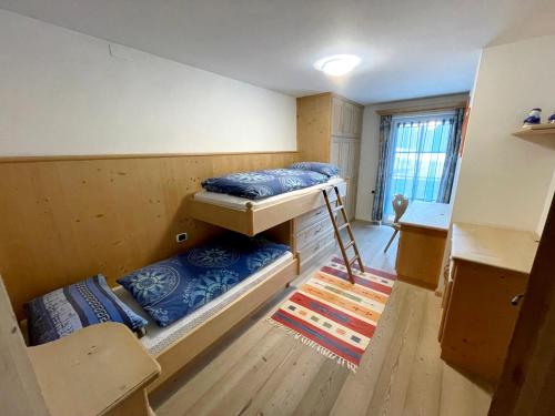 索拉加Ciasa Rossi的客房设有两张双层床和一张桌子。