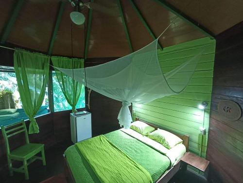 科克莱斯Finca Valeria Treehouses Glamping的一间卧室配有一张带天蓬的绿色床