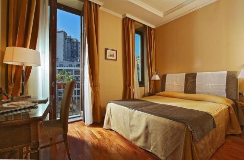 那不勒斯图尔基尼宫酒店的一间卧室配有一张床、一张书桌和一个窗户。