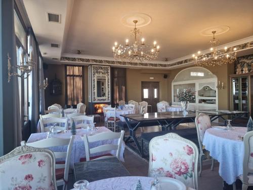 埃拉托克里昂Nikelli的餐厅配有白色的桌椅和吊灯