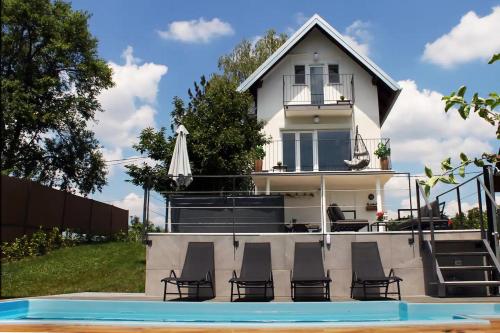 GudciHouse with hot tub, sauna and swimming pool near Zagreb的房屋前设有椅子和游泳池