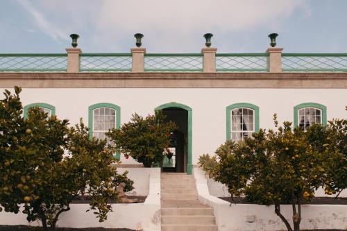 阿里亚Hotel Emblemático La Casa de los Naranjos的白色的建筑,有绿色的屋顶和楼梯