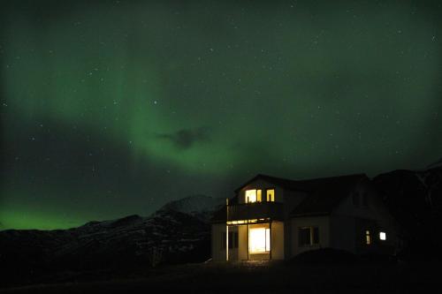 霍芬Sauðanes Guesthouse的夜晚在绿色的北极光下的房子
