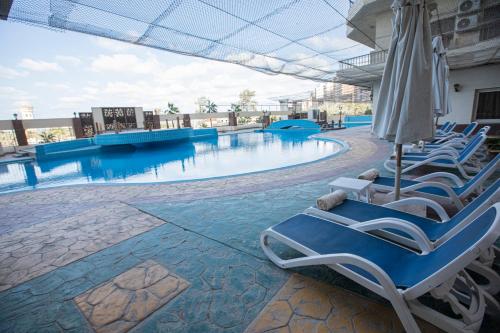 亚历山大AIFU Hotel El Montazah Alexandria的一个带躺椅和遮阳伞的游泳池