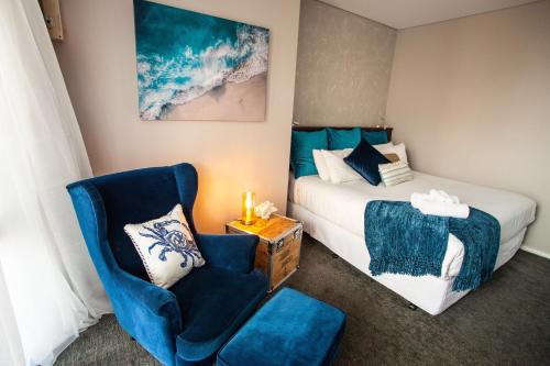 弗里曼特Fremantle Boutique Accommodation - Maand Up的一间卧室配有一张床、一张蓝色椅子、一张床和椅子