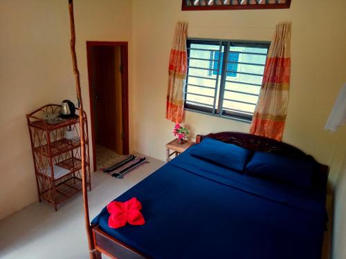 高龙撒冷岛Baloo Guesthouse的一间卧室配有一张蓝色的床,上面有红色的弓