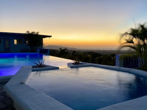 普拉亚科罗纳多Hotel Eclipse, Playa Coronado的一座游泳池,位于一座享有日落美景的房屋前