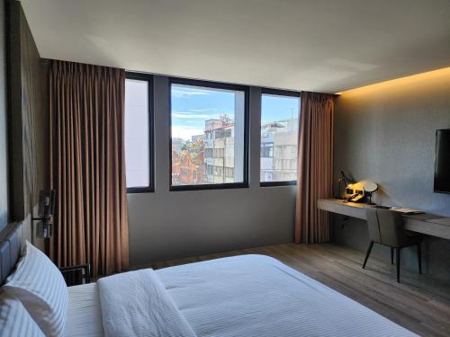 花莲市花蓮品悅文旅Hualien Pink Corner Hotel的卧室配有一张床、一张书桌和窗户。