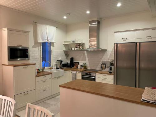 坦佩雷Modern 6-bedroom villa near Tampere city的厨房配有白色橱柜和不锈钢冰箱
