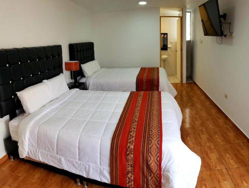 库斯科Hostal Cusco de mis Sueños的一间卧室配有两张床和一台平面电视