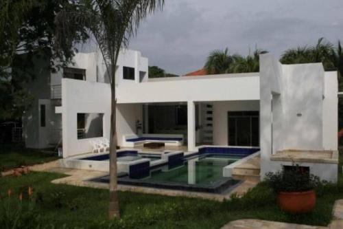 里考尔特Casa Girardot的一座带游泳池和棕榈树的白色房子