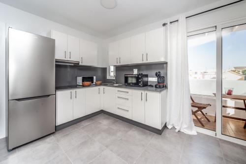 宏达海滩Luxury Beach Apartments Diama的厨房配有白色橱柜和不锈钢冰箱