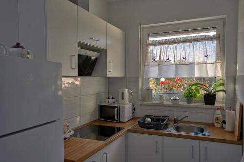 隆代克-兹德鲁伊Pensjonat Na Każdą Porę的厨房配有白色橱柜、水槽和窗户。