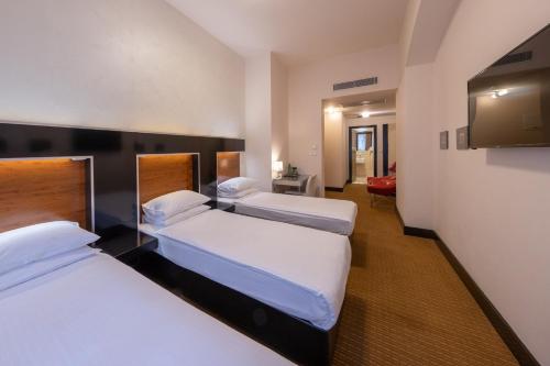 布拉格Grand Majestic Hotel Prague的酒店客房设有两张床和一台平面电视。