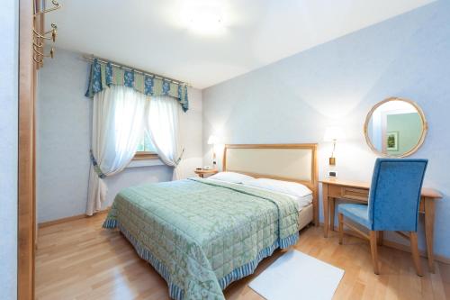 博尔扎诺Residence Werth的一间卧室配有一张床、一张书桌和一面镜子
