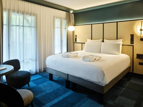 勒图凯-巴黎普拉日Mercure Hôtel Le Touquet的酒店客房设有一张大床和一张书桌。