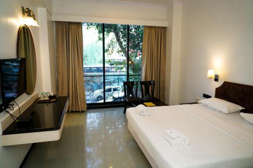 孟买Hotel Sun Shine Inn的酒店客房设有一张床和一个大窗户