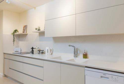 耶路撒冷The Pearl of Nachlaot Apartments的白色的厨房配有白色橱柜和水槽