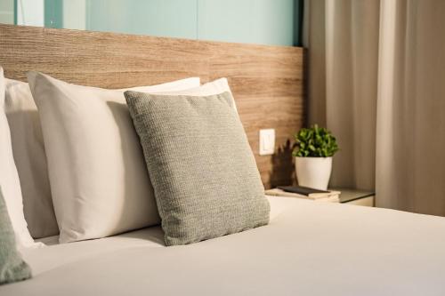 埃尔哥茨拉115 The Strand Hotel by NEU Collective的一张带白色枕头和木制床头板的床