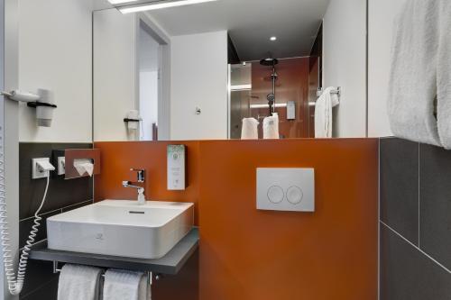 慕尼黑Campanile Muenchen Sendling的浴室设有白色水槽和橙色墙壁。