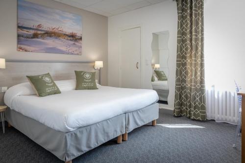 洛里昂Logis REX HOTEL Lorient的卧室配有带绿色枕头的大型白色床