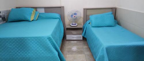 阿蒂加斯FAGO的卧室内的两张床,配有蓝色床单和风扇