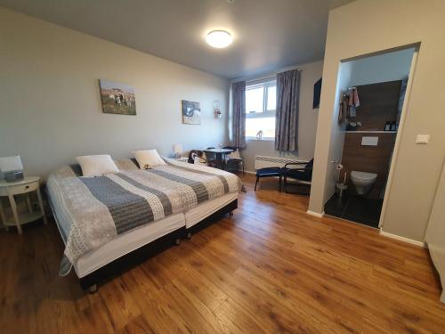 Skálatjörn斯卡拉特若旅馆的铺有木地板的客房内设有一间卧室和一张床。