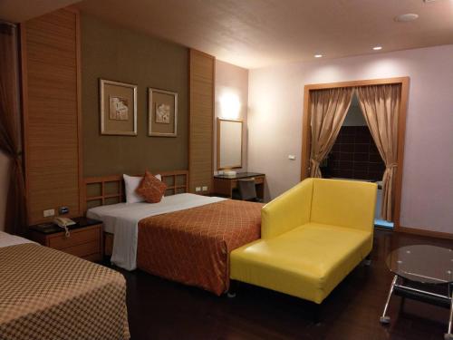 高雄Lisa Motel的酒店客房,设有两张床和一张黄色椅子