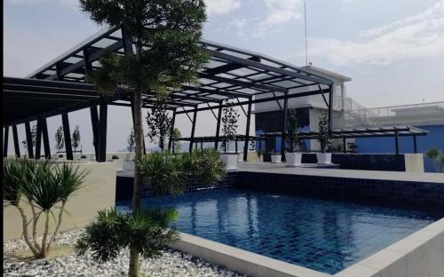 Kampong Lumut Kiri休闲民宿 Leisure Homestay @The Venus Sitiawan的一座大楼前的游泳池,游泳池内有树冠和树木