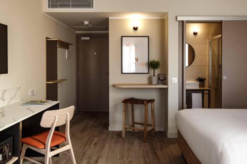 埃尔哥茨拉Strand Suites by NEU Collective的一间卧室配有一张床、一张桌子和一把椅子