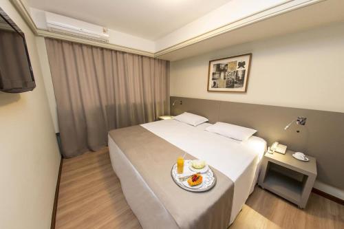 库里提巴阿尔塔雷吉亚广场酒店的酒店客房,配有一张带一盘食物的床