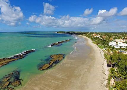 塔曼达雷Praia dos carneiros flat hotel的享有岩石海滩和海洋的空中景致