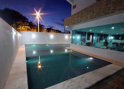 塔曼达雷Praia dos carneiros flat hotel的一座游泳池,在晚上在建筑物前