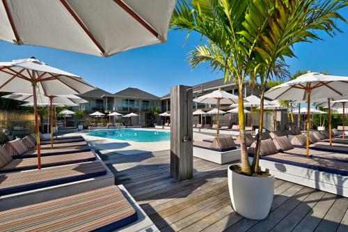 蒙托克蒙托克海滨别墅酒店的一个带椅子和遮阳伞的游泳池以及棕榈树
