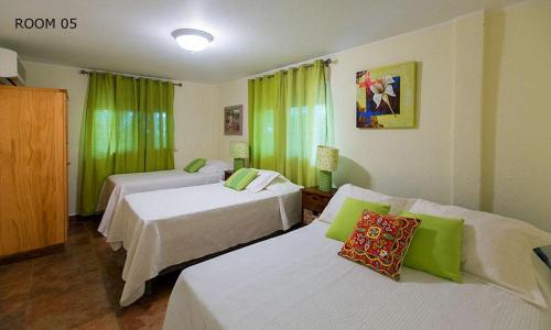 蓬塔查梅HOTEL CASA AMARILLA et RESTAURANT的酒店客房,设有两张床和绿色窗帘