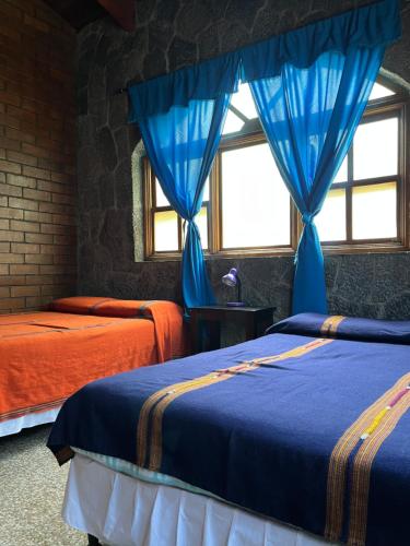 San Lucas TolimánCasa Qatzij - Guest House, Lake Atitlan的一间卧室配有两张蓝色窗帘的床