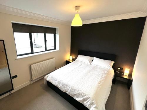 泰晤士河畔金斯顿Modern and cozy 2-guest flat with gated parking的卧室配有白色的床和窗户。