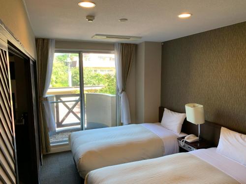 富士河口湖Kawaguchiko Park Hotel的酒店客房设有两张床和窗户。