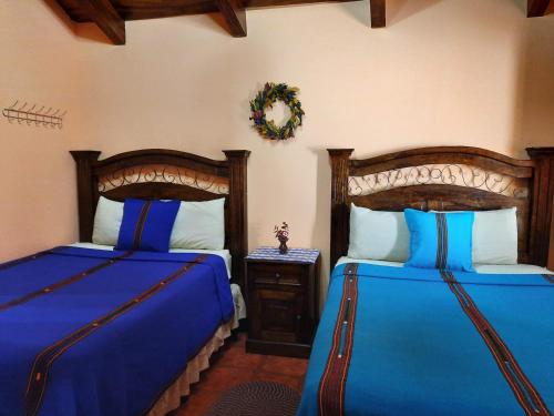 危地马拉安地瓜Hotel Casa Sofia的一间卧室配有两张带蓝色床单的床和一张桌子