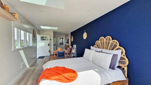 帕帕库拉Retro on Queen, Papakura的一间卧室设有蓝色的墙壁和一张带橙色毯子的床。