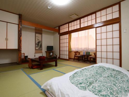 SanmuSeaside Hotel Kujukuri的一间设有床铺和桌子的房间